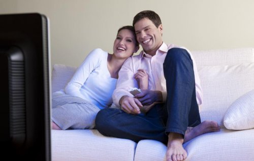 Casais felizes assistem tv juntos