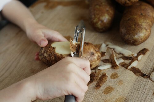 Mulher descascando batata para preparar um creme de batatas