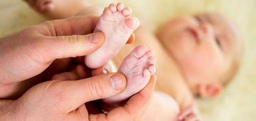 Pai fazendo massagens no bebê para aliviar a dor abdominal