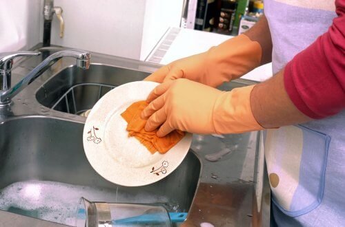 Mulher usando produtos de limpeza para lavar louça
