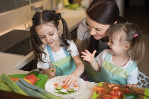 Meninas preparando pratos adequados para o desenvolvimento ósseo de crianças