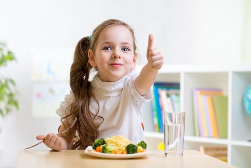 Menina tomando água enquanto come os alimentos certos