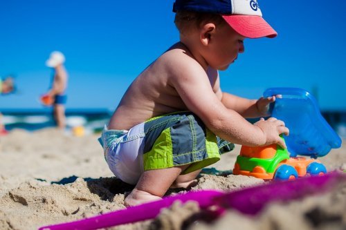 Menino brincando na areia da praia