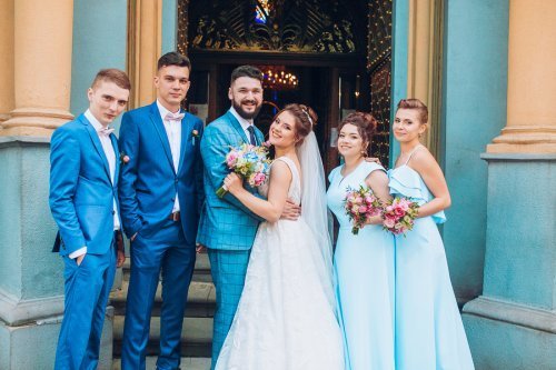 Casal de noivos e padrinhos posando na porta da igreja