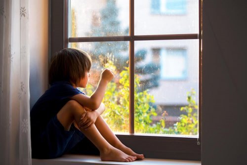 Criança triste olhando pela janela.