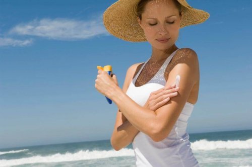Mulher passando protetor solar no corpo