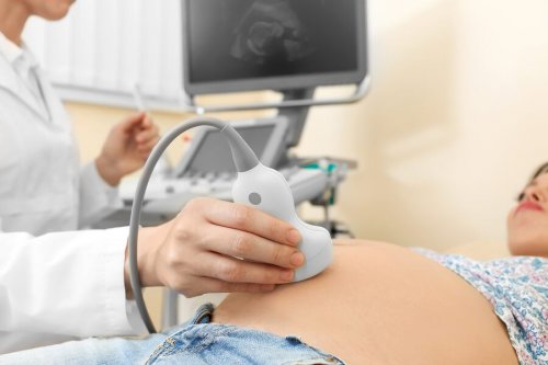 Médico realizando ultrassom abdominal para uma mulher grávida