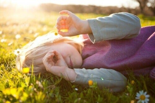Menina deitada na grama com uma flor na mão, gerando lembranças de namoro infantil