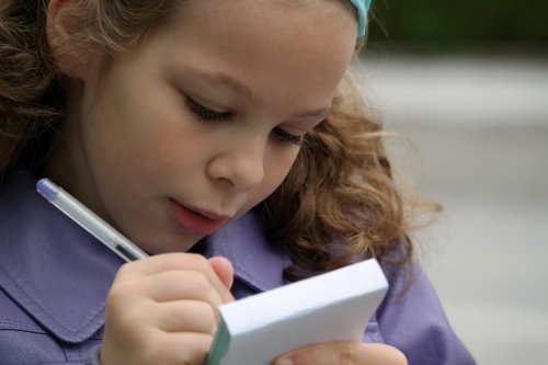 Menina escrevendo com caneta em um caderno