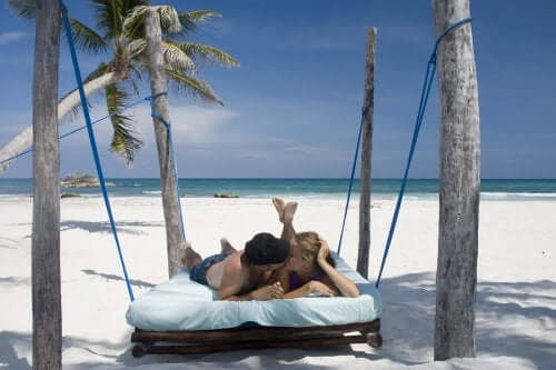 Casal em uma cama na praia beijando