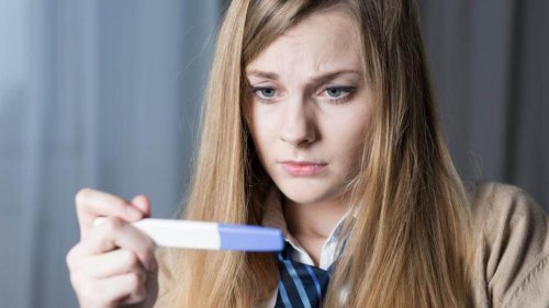 Mulher conferindo um teste de gravidez. Tipos de aborto