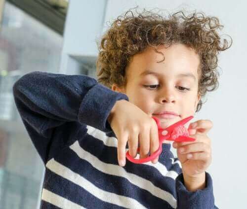 Criança usando uma tesoura para fazer artesanato.