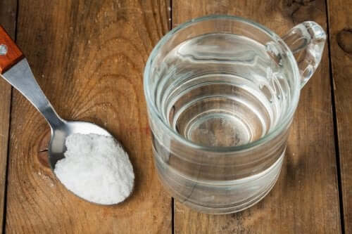 Um copo de água e uma colher com bicarbonato de sódio