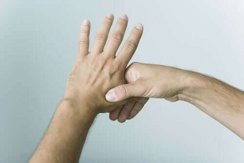 Mão segurando o polegar da outra mão