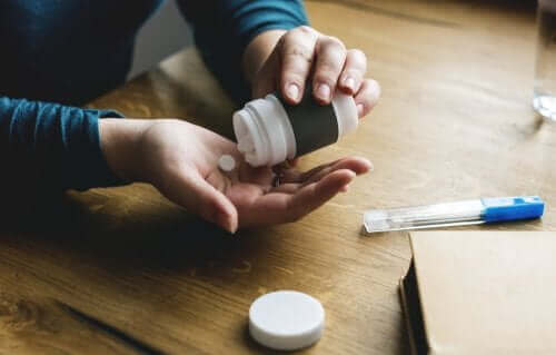 Uma pessoa que pega uma pílula de um recipiente anti-inflamatórios não esteroides