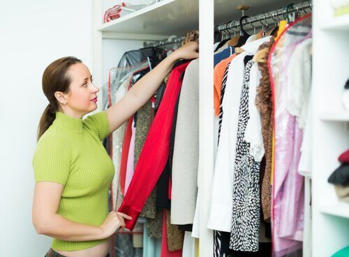 Mulher revisando as roupas do seu armário