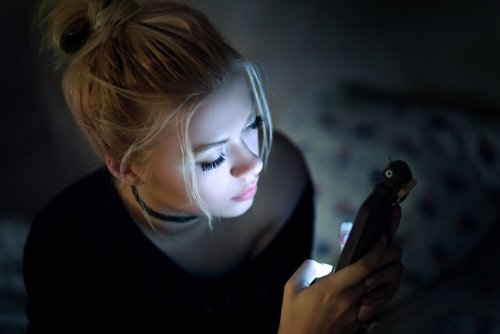 Mulher olhando celular no escuro