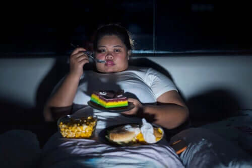 Mulher obesa comendo e vendo televisão