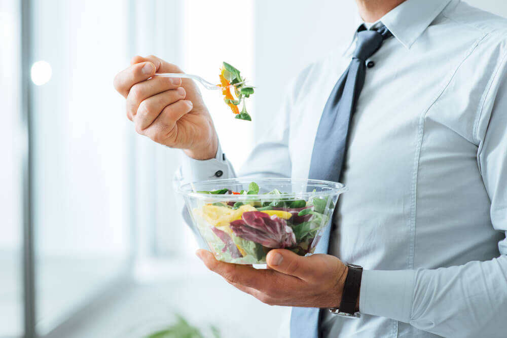 Homem comendo salada no trabalho