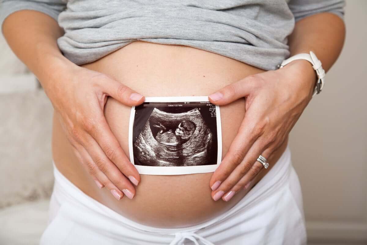 Mulher grávida segurando foto do ultrassom