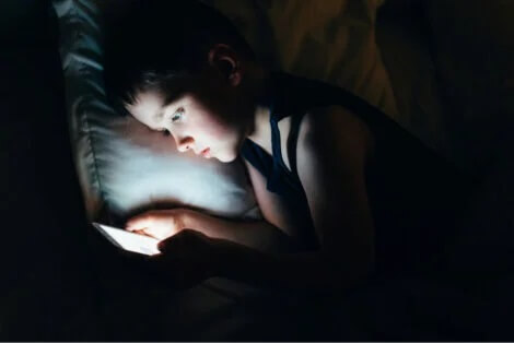 Criança com celular no escuro
