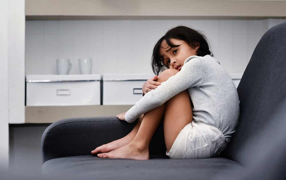 Menina encolhida em sofá